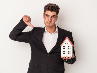 homme pouce vers le bas tenant une maquette maison