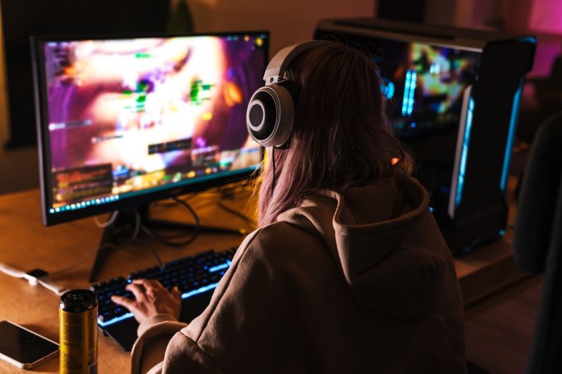 fille avec casque sur la tête devant un écran d'ordinateur