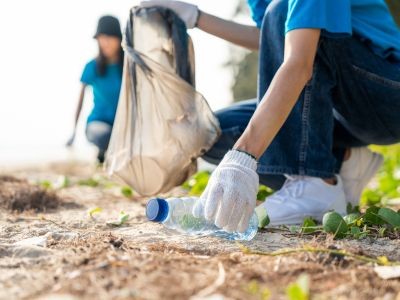 femme rammassant bouteille en plastque sur la plage