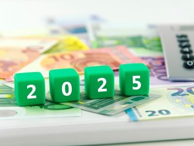 Cubes verts affichant l'année 2025 posés sur des billets d'euros avec une calculatrice à l'arrière-plan