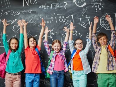 enfants levant les bras devant  tableau noir