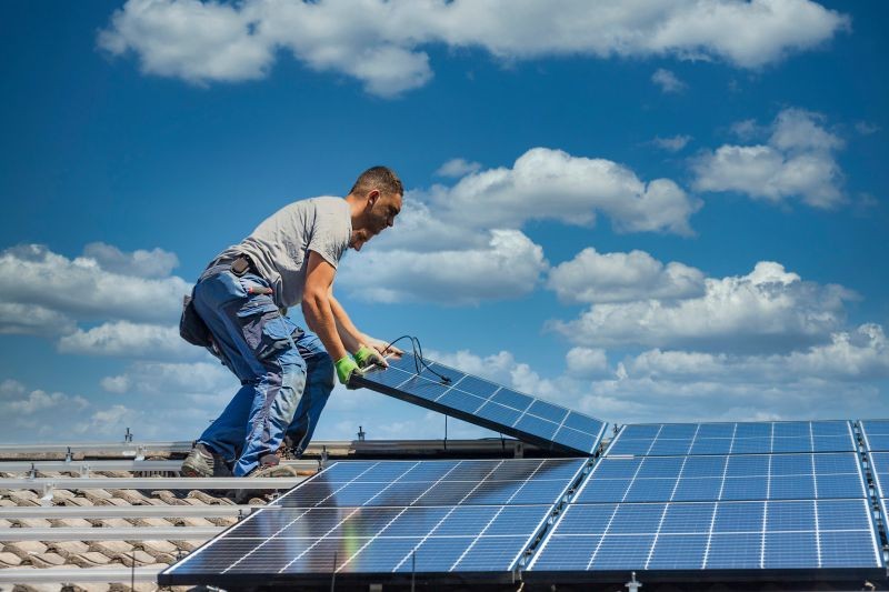 homme sur un toit panneaux photovoltaïques